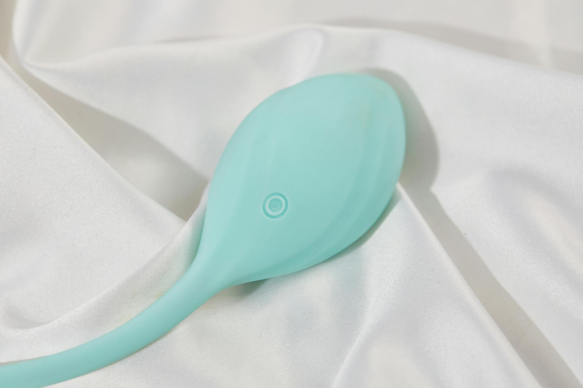 A sleek teal lemon vibrator on white silk, ready for quick pleasure