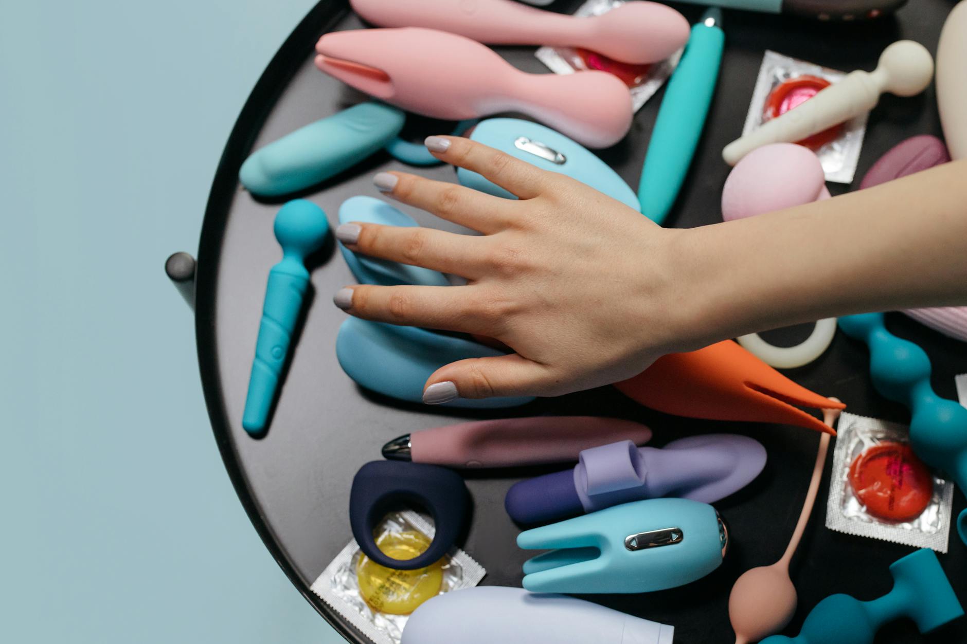 A blue silicone clitoral vibrator held in hand against a solid purple background, promoting self-love and sexuality during recovery